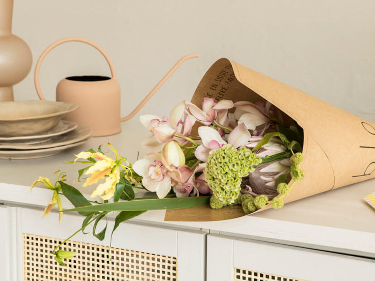 Deluxe Bouquet in Kartonverpackung auf einem weißen Schrank  
