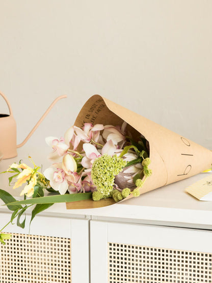Deluxe Bouquet in Kartonverpackung auf einem weißen Schrank  